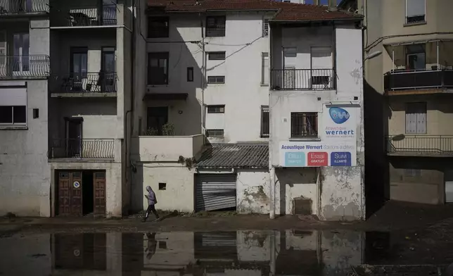 A man walks in a flooded street in Rive-de-Gier, central France, after torrential rains and flooding submerged roads and railways, Friday, Oct. 18, 2024. (AP Photo/Laurent Cipriani)