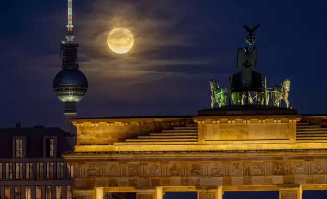 The full Hunters Supermoon rises next to the Quadriga on top of the Brandenburg Gate in Berlin, Germany, Thursday, Oct. 17, 2024. (AP Photo/Michael Probst)