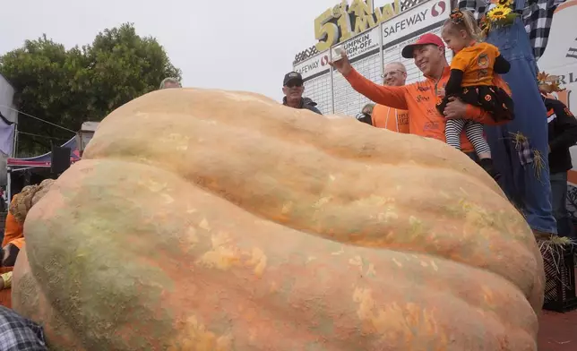 Travis Gienger, of Anoka, Minn., second from right, celebrates with his daughter Lily, 3, after his pumpkin weighed in at 2,471 pounds to win at the Safeway World Championship Pumpkin Weigh-Off in Half Moon Bay, Calif., Monday, Oct. 14, 2024. (AP Photo/Jeff Chiu)