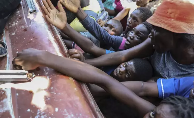 People displaced by armed attacks receive food from a nongovernmental organization in Saint-Marc, Haiti, Sunday, Oct. 6, 2024. (AP Photo/Odelyn Joseph)