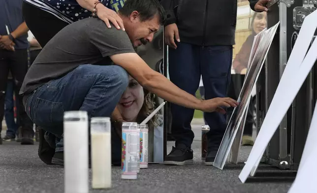 Daniel Delgado reaches to touch a photo of his wife, Monica Hernandez, who died at Impact Plastics during flooding caused by Hurricane Helene, at a vigil for victims of the tragedy in Erwin, Tenn., on Thursday, Oct. 3, 2024. (AP Photo/Jeff Roberson)