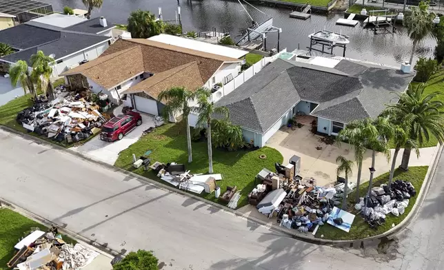 Debris from homes flooded in Hurricane Helene is piled curbside as Hurricane Milton approaches on Tuesday, Oct. 8, 2024, in Port Richey, Fla. (AP Photo/Mike Carlson)