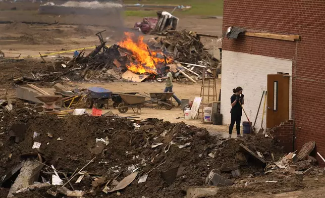 People clean up and burn debris left in the aftermath of Hurricane Helene Friday, Oct. 4, 2024, in Erwin, Tenn. (AP Photo/Jeff Roberson)