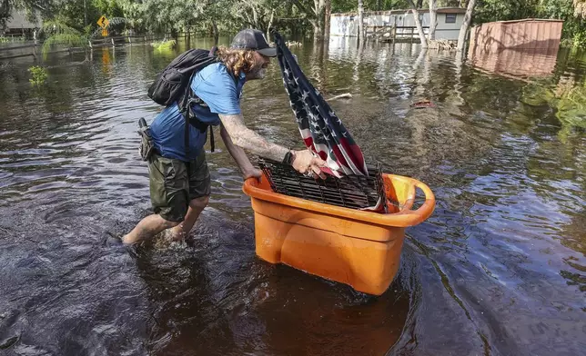 A man who identified himself as Jesse walks out through floodwaters of the Anclote River after Hurricane Milton hit the region, Thursday, Oct. 10, 2024, in New Port Richey, Fla. (AP Photo/Mike Carlson)