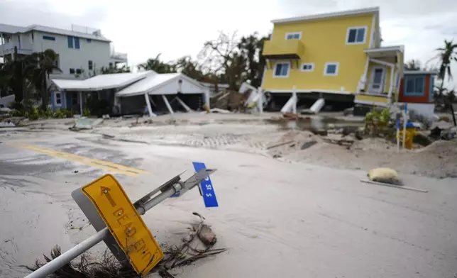 A house sits toppled off its stilts after the passage of Hurricane Milton, alongside an empty lot where a home was swept away by Hurricane Helene, in Bradenton Beach on Anna Maria Island, Fla., Thursday, Oct. 10, 2024. (AP Photo/Rebecca Blackwell)