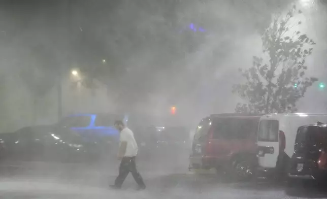 Max Watts, of Buford, Ga., walks in the parking lot to check on a trailer parked outside the hotel where he is riding out Hurricane Milton with coworkers, Wednesday, Oct. 9, 2024, in Tampa, Fla. Watts, who works for a towing company, was deployed with colleagues to Florida to aid in the aftermath of the storm. (AP Photo/Julio Cortez)