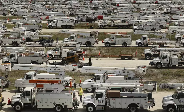 Duke Energy project manager Tiger Yates, bottom center, walks among the hundreds of lineman trucks staged, Tuesday, Oct. 8, 2024. at The Villages, Fla. in preparation for Hurricane Milton. (Stephen M. Dowell/Orlando Sentinel via AP)