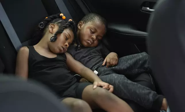 Siblings Saboria, 4, left, and Messiah Tyler, 3, nap in the backseat of a car after the roof was torn off the home where they lived with their mom, grandparents, an aunt and an uncle during the passage of Hurricane Milton, in Palmetto, Fla., Thursday, Oct. 10, 2024. The family of 7 rode out the storm in a government shelter, and returned home to find most of the roof gone and their furniture and belongings destroyed by rainwater. (AP Photo/Rebecca Blackwell)