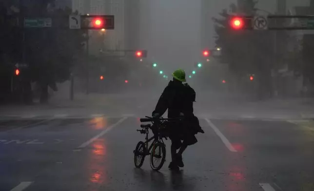 Ron Rook, who said he was looking for people in need of help or debris to clear, walks through windy and rainy conditions on a deserted street in downtown Tampa, Fla., during the approach of Hurricane Milton, Wednesday, Oct. 9, 2024. (AP Photo/Rebecca Blackwell)