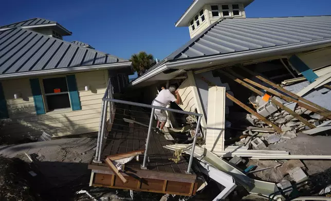 A property owner who preferred not to give his name peers into the remains of the second floor unit where he lived with his wife while renting out the other units, on Manasota Key, in Englewood, Fla., following the passage of Hurricane Milton, Sunday, Oct. 13, 2024. (AP Photo/Rebecca Blackwell)