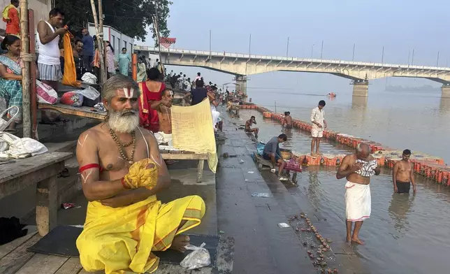 A Hindu priest prays as devotees take a holy dip in the Saryu river on the morning of Deepotsav celebrations, an event organized by the Uttar Pradesh state government on the eve of Diwali, in Ayodhya, India, Wednesday, Oct. 30, 2024. (AP Photo/Rajesh Kumar Singh)