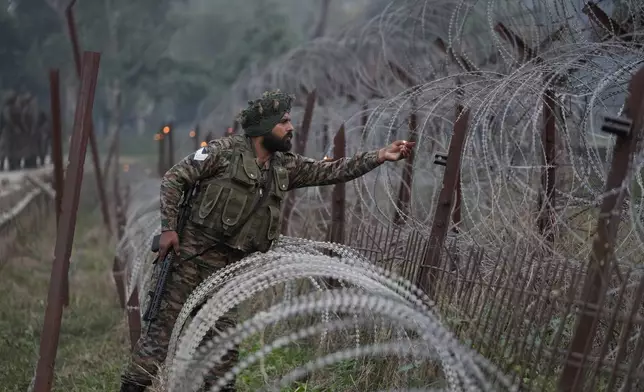 An Indian army soldier lights an earthen lamp on a fence to celebrate Diwali, near the Line of Control that divides Kashmir region between India and Pakistan, in Akhnoor sector, Jammu and Kashmir, India, Monday, Oct. 28, 2024.(AP Photo/Channi Anand)