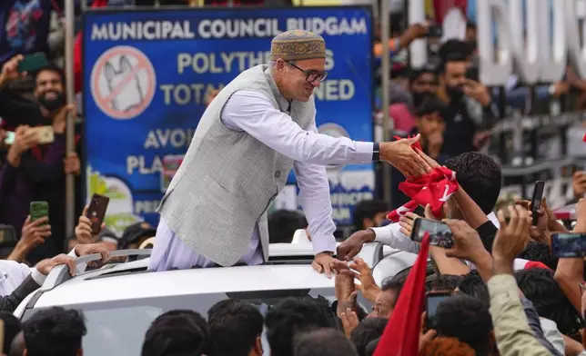 Jammu and Kashmir National Conference (JKNC) party leader Omar Abdullah, standing in car shakes hands with supporters as he celebrates his victory in the election for a local government in Indian controlled Kashmir, Budgam, Tuesday, Oct. 8, 2024. (AP Photo/Dar Yasin)