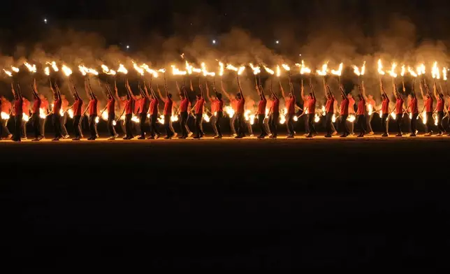 Artists carry burning torches as they perform during a cultural show as part of the Dussehra festivities in Mysuru, India, Friday, Oct. 11, 2024. (AP Photo/Aijaz Rahi)