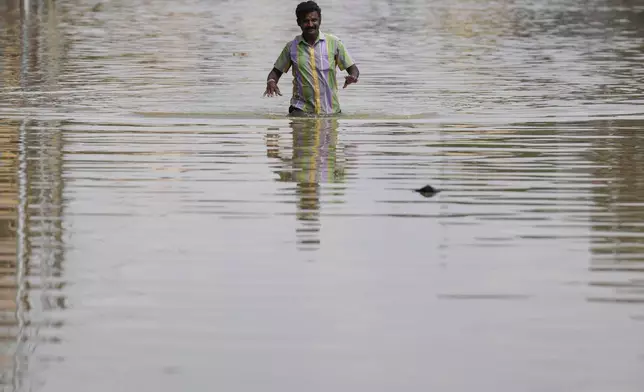 A man wades through a flooded street after heavy rains in Bengaluru, India, Tuesday, Oct. 22, 2024. (AP Photo/Aijaz Rahi)