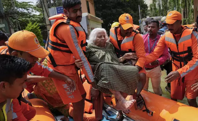 Lakshmi, is carried by rescue workers on her 86th birthday, after she was rescued from a flooded residential apartment due to heavy rains in Bengaluru, India, Tuesday, Oct. 22, 2024. (AP Photo/Aijaz Rahi)