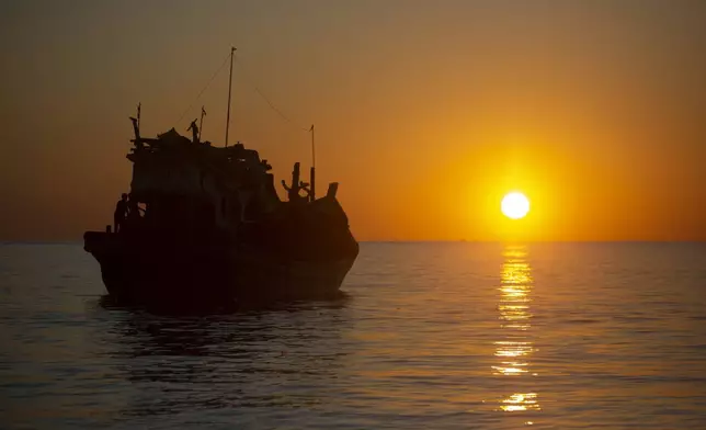 A boat carrying Rohingya refugees anchors near the coast of Labuhan Haji, Aceh province, Indonesia, as the sun sets Tuesday, Oct. 22, 2024. (AP Photo/Binsar Bakkara)