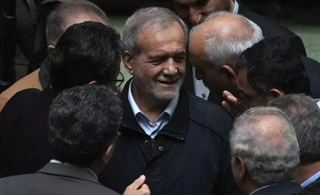 Iranian President Masoud Pezeshkian, center, listens to a lawmaker after speaking on his next year's budget bill in an open session of parliament, in Tehran, Iran, Tuesday, Oct. 29, 2024. (AP Photo/Vahid Salemi)