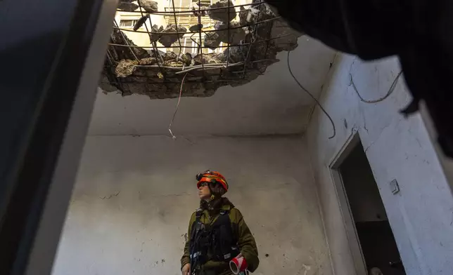 An officer from the home front command military unit examines the damaged apartment after it was hit by a rocket fired from Lebanon in Kiryat Yam, northern Israel, Tuesday, Oct. 8, 2024. (AP Photo/Ariel Schalit)