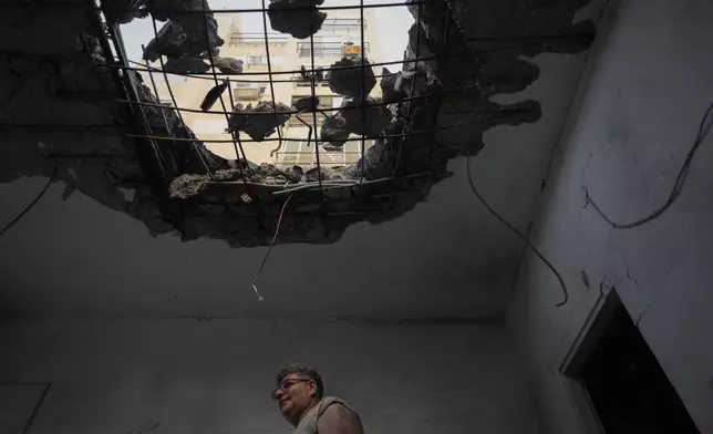 A man examine his damaged apartment that was hit by a rocket fired from Lebanon in Kiryat Yam, northern Israel, on Tuesday, Oct. 8, 2024. (AP Photo/Ariel Schalit)