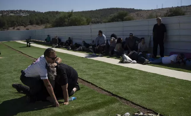 People take cover as a siren warns of incoming rockets during the funeral of Alexei Popov, who was killed during a rocket attack fired from Lebanon last weekend, at the Tel Regev cemetery in the outskirts of Haifa, northern Israel, Monday, Oct. 21, 2024. (AP Photo/Leo Correa)