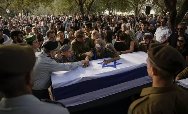 People mourn over the flagged-covered coffin of Israeli soldier Sgt. Amitai Alon, killed by a Hezbollah drone attack, during his funeral near Ramot Naftali, Israel, Monday, Oct. 14, 2024. (AP Photo/Leo Correa)