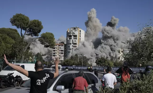 People react as smoke rises from a building that was hit by an Israeli missile in Ghobeiri, Beirut, Lebanon, Tuesday, Oct. 22, 2024. (AP Photo/Bilal Hussein)