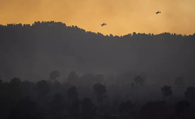 Israeli firefighting planes fly over smoke from a fire after a rocket, fired from Lebanon, hit the area near Hatzor Haglilit, northern Israel, Wednesday, Oct. 9, 2024. (AP Photo/Leo Correa)