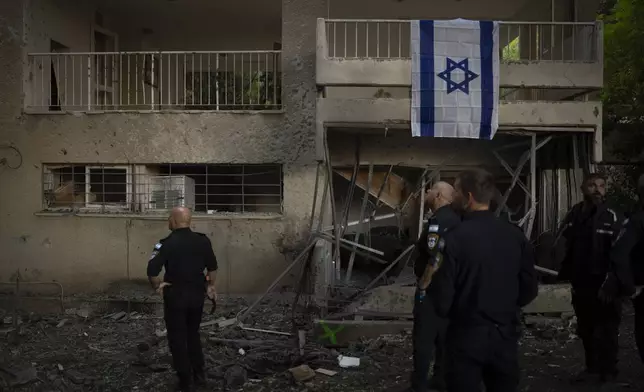 Israeli police officers stand in front of an apartment, that was damaged by a rocket fired from Lebanon, in Karmiel, northern Israel, Thursday, Oct. 24, 2024. (AP Photo/Leo Correa)