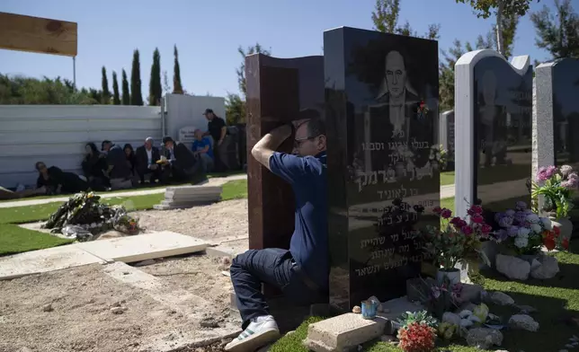 People take cover as a siren warns of incoming rockets during the funeral of Alexei Popov, who was killed during a rocket attack fired from Lebanon last weekend, at the Tel Regev cemetery in the outskirts of Haifa, northern Israel, Monday, Oct. 21, 2024. (AP Photo/Leo Correa)