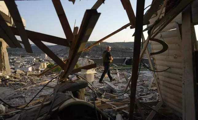 Israeli security forces survey damage to a home struck by a rocket fired from Lebanon in the town of Majd al-Krum, northern Israel, Wednesday, Oct. 16, 2024. (AP Photo/Ariel Schalit)