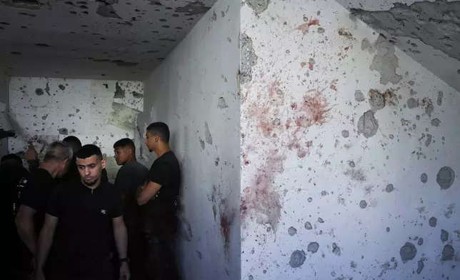 Neighbors examine the damaged house where one person was killed after a projectile launched from Lebanon slammed into Maalot-Tarshiha, northern Israel, Tuesday, Oct. 29, 2024. (AP Photo/Ohad Zwigenberg)