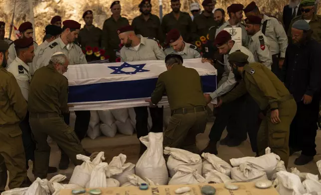 Israeli soldiers lower into the grave the flagged-covered coffin of reservist Yedidia Bloch, 31, during his funeral at Mevo Horon settlement, West Bank, Wednesday, Oct. 30, 2024. Bloch died on Tuesday 29 after he was injured in Lebanon. (AP Photo/Francisco Seco)