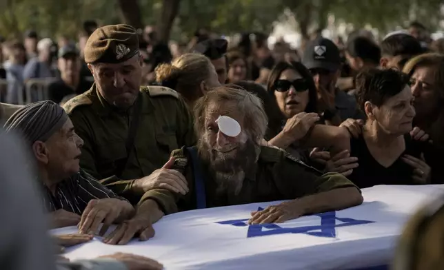 People mourn over the flagged-covered coffin of Israeli soldier Sgt. Amitai Alon, killed by a Hezbollah drone attack, during his funeral near Ramot Naftali, Israel, Monday, Oct. 14, 2024. (AP Photo/Leo Correa)