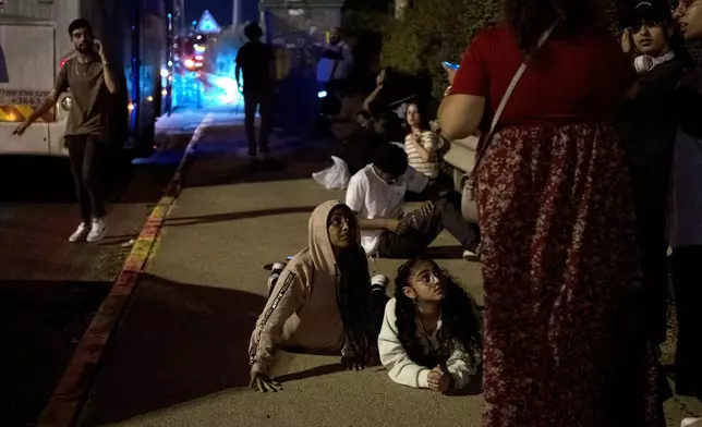 Israelis wait to re-board their bus after projectiles were launched from Iran are being intercepted in the skies over in Rosh HaAyin, Israel, Tuesday, Oct. 1, 2024. (AP Photo/Maya Alleruzzo)