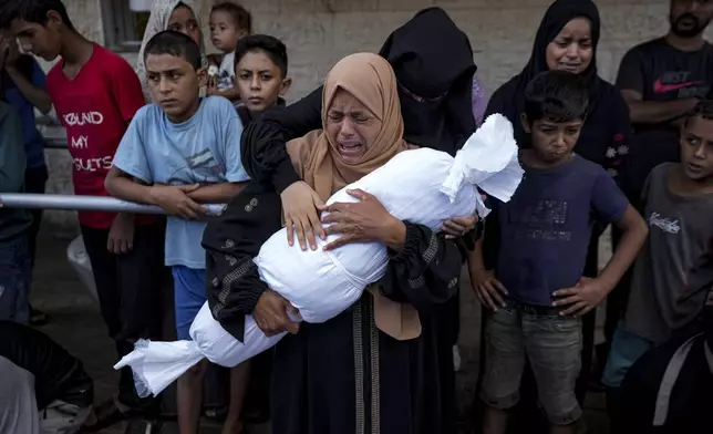 Palestinians mourn relatives killed in the Israeli bombardment of the Gaza Strip, at a hospital in Deir al-Balah, Tuesday, Oct. 1, 2024. (AP Photo/Abdel Kareem Hana)