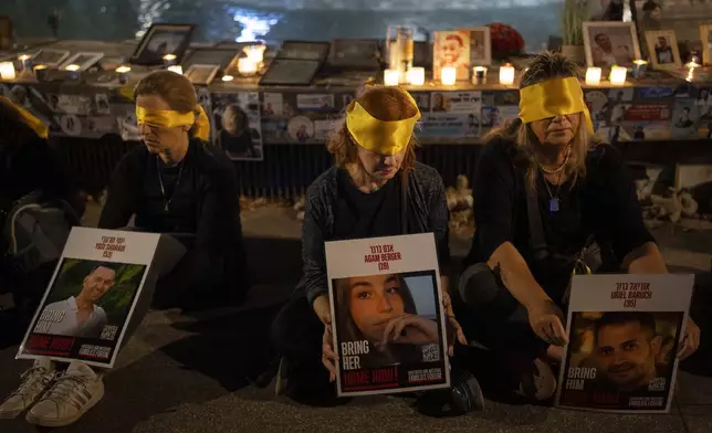 Activists sit blindfolded to mark one year in the Hebrew calendar since the Hamas cross-border attack on Israel in a protest against the celebration of the Jewish holiday of Simchat Torah while hostages are still held in Gaza, in Tel Aviv, Israel, Thursday, Oct. 24, 2024. (AP Photo/Oded Balilty)