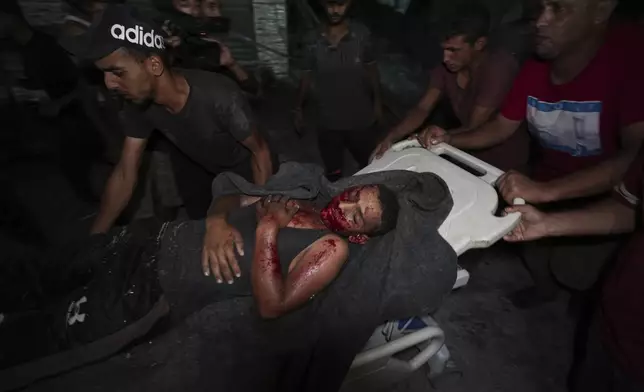 Palestinians carry an injured man from a destroyed mosque following an Israeli airstrike in Deir al-Balah, Sunday, Oct. 6, 2024. (AP Photo/Abdel Kareem Hana)