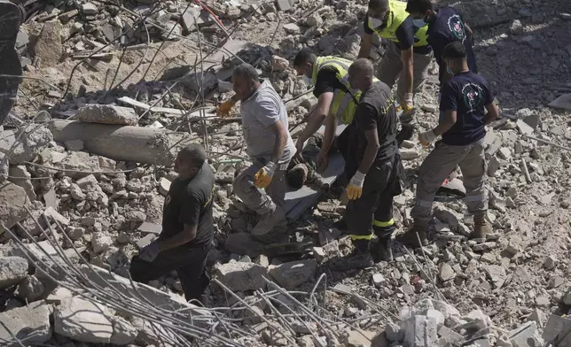 Rescue workers carry the body of a boy who was found under the rubble of a destroyed building that was hit Tuesday night in an Israeli airstrike, in Sarafand, south Lebanon, Wednesday, Oct. 30, 2024. (AP Photo/Bilal Hussein)