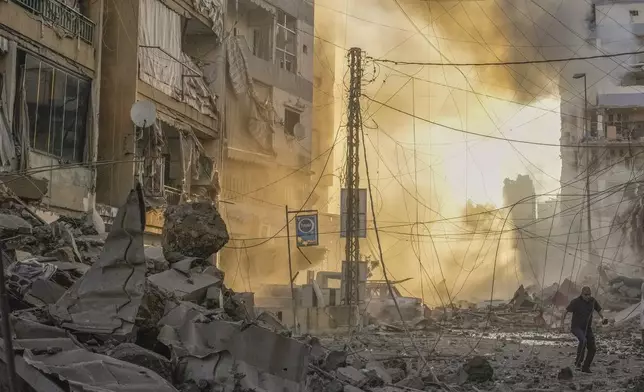 A man runs for cover as a smoke raises in the background following an Israeli airstrike in Dahiyeh, Beirut, Lebanon, Friday, Oct. 4, 2024. (AP Photo/Hassan Ammar)