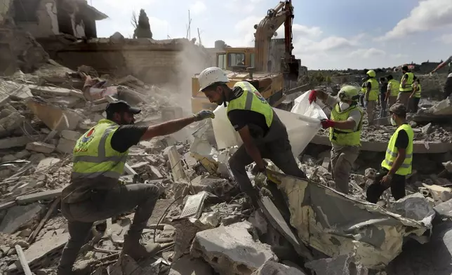 Rescue workers carry remains of people at at site that was hit by Israeli airstrikes in Qana village, south Lebanon, Wednesday, Oct. 16, 2024. (AP Photo/Mohammed Zaatari)