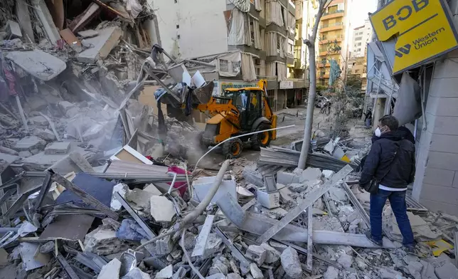 Rescue workers use a bulldozer to remove rubble of destroyed buildings at the site of an Israeli airstrike on Sunday night that hit several branches of the Hezbollah-run al-Qard al-Hassan in Beirut's southern suburb, Lebanon, Monday, Oct. 21, 2024. (AP Photo/Hassan Ammar)