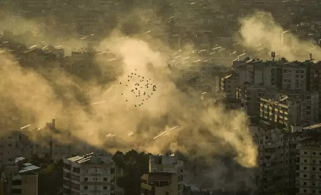 A flock of birds fly as smoke rises from the site of an Israeli airstrike in Dahiyeh, in the southern suburb of Beirut, Lebanon, Thursday, Oct. 24, 2024. (AP Photo/Bilal Hussein)