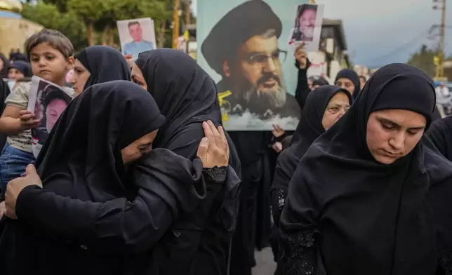 Mourners carry a picture of slain Hezbollah leader Hassan Nasrallah during the funeral procession of their relatives, in Maisara near the northern coastal town of Byblos, Lebanon, Monday, Oct. 14, 2024. (AP Photo/Hassan Ammar)