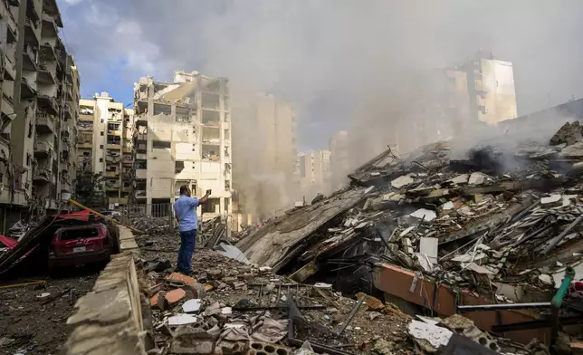 A man documents the damaged buildings at the site of an Israeli airstrike in Beirut's southern suburb, Lebanon, Tuesday, Oct. 1, 2024. (AP Photo/Hassan Ammar)