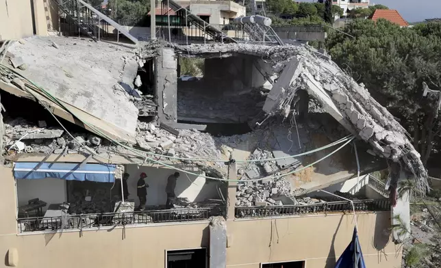 Rescue workers search for victims on a hotel-turned-shelter for displaced people hit by an Israeli airstrike, in Wardaniyeh, south Lebanon, Wednesday, Oct. 9, 2024. (AP Photo/Mohammed Zaatari)