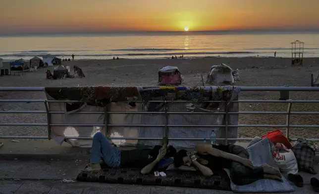 Men sleep at the Ramlet al-Baida public beach after fleeing the Israeli airstrikes in Dahiyeh, Beirut, Lebanon, Tuesday, Oct. 8, 2024. (AP Photo/Bilal Hussein)