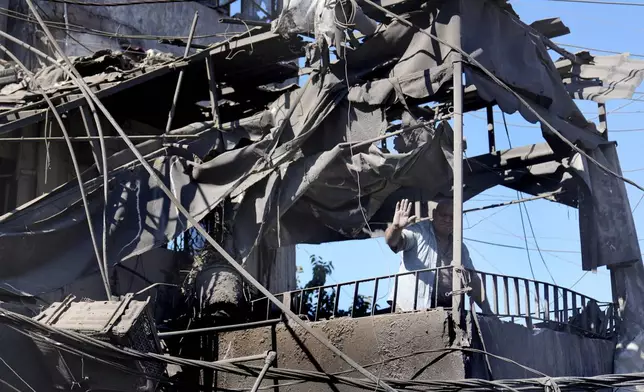 A man waves from his shattered house at the site of Israeli airstrikes that destroyed buildings facing the city's main government hospital in a densely-populated neighborhood, in southern Beirut, Lebanon, Tuesday, Oct. 22, 2024. (AP Photo/Hussein Malla)