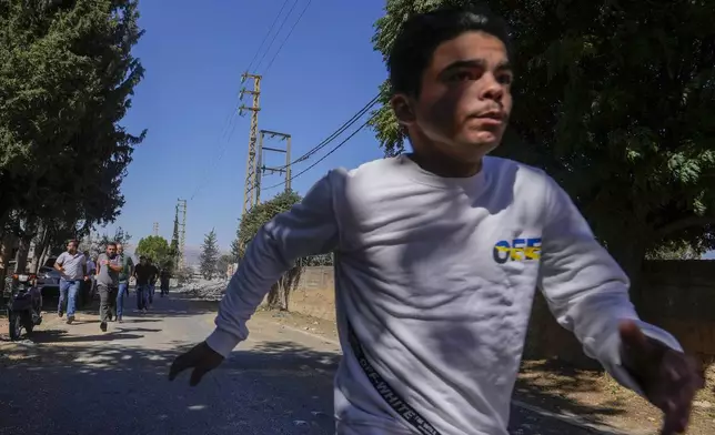 Journalists and residents run for cover following an Israeli airstrike in Baalbek, east Lebanon, Sunday, Oct. 6, 2024. (AP Photo/Hassan Ammar)