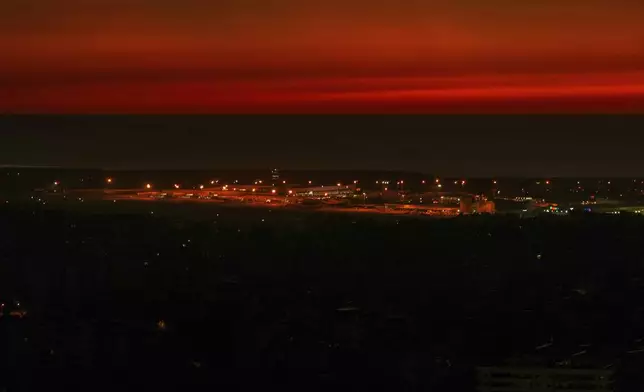 The twilight sky glows after sunset over Beirut's Rafik Hariri International Airport as Beirut's Dahiyeh suburb, foreground, remains in darkness after Israeli airstrikes, Beirut, Monday, Oct. 28, 2024. (AP Photo/Hassan Ammar)